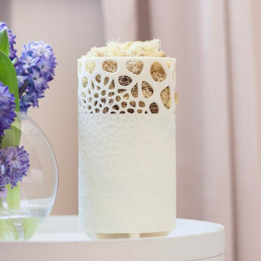 Mossy Air Purifier on a white table together with purple flowers in a vase